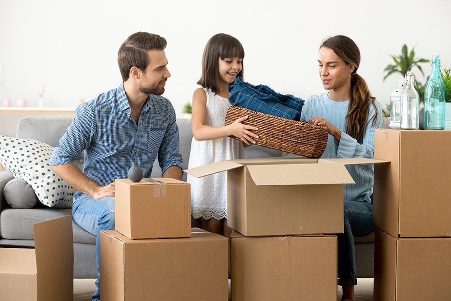Personal Insurance - A Happy Family are Sitting on a Sofa and Unpacking Boxes into Their New Home